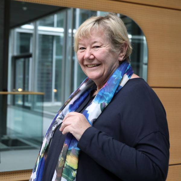 „Lobby für Mädchen“-Mitbegründerin und Geschäftsführerin Frauke Mahr steht lächelnd vor einem großen Spiegel, sie trägt ein dunkelblaues Kleid und ein blau-weißes Tuch mit Blumenprint-