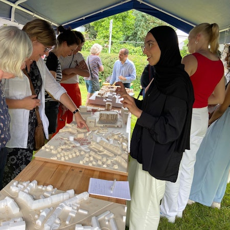 Frauen stehen um ein Architekturmodell auf einem Tisch