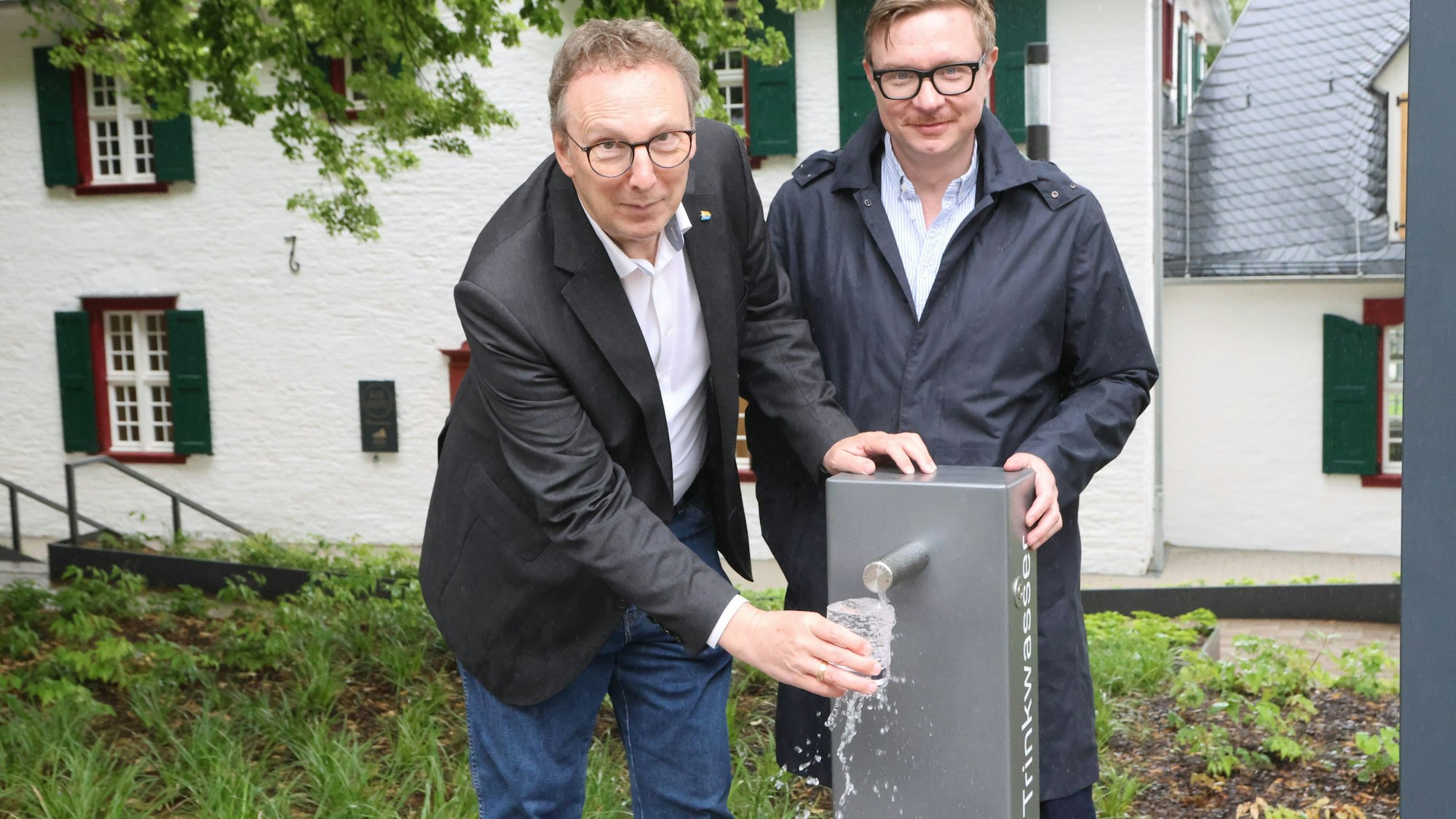 Das Foto zeigt einen Trinkwasserspender in der Kaiserstraße und zwei Männer.