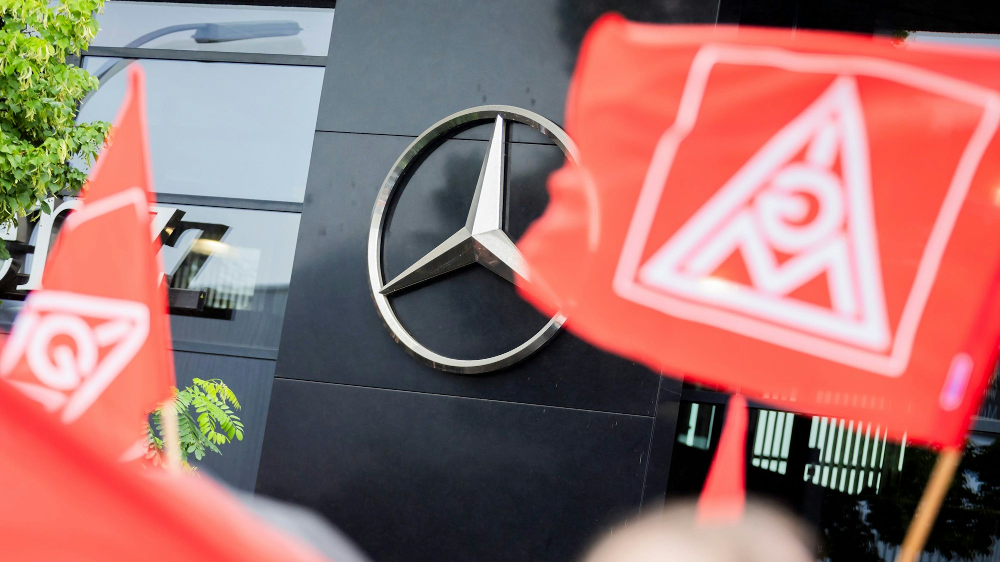Flaggen der IG-Metall sind bei einer Kundgebung im Rahmen eines bundesweiten Aktionstages für die Zukunft der Beschäftigten der Mercedes-Benz Niederlassungen vor dem dem Berliner Mercedes-Benz-Niederlassungscenter zu sehen.