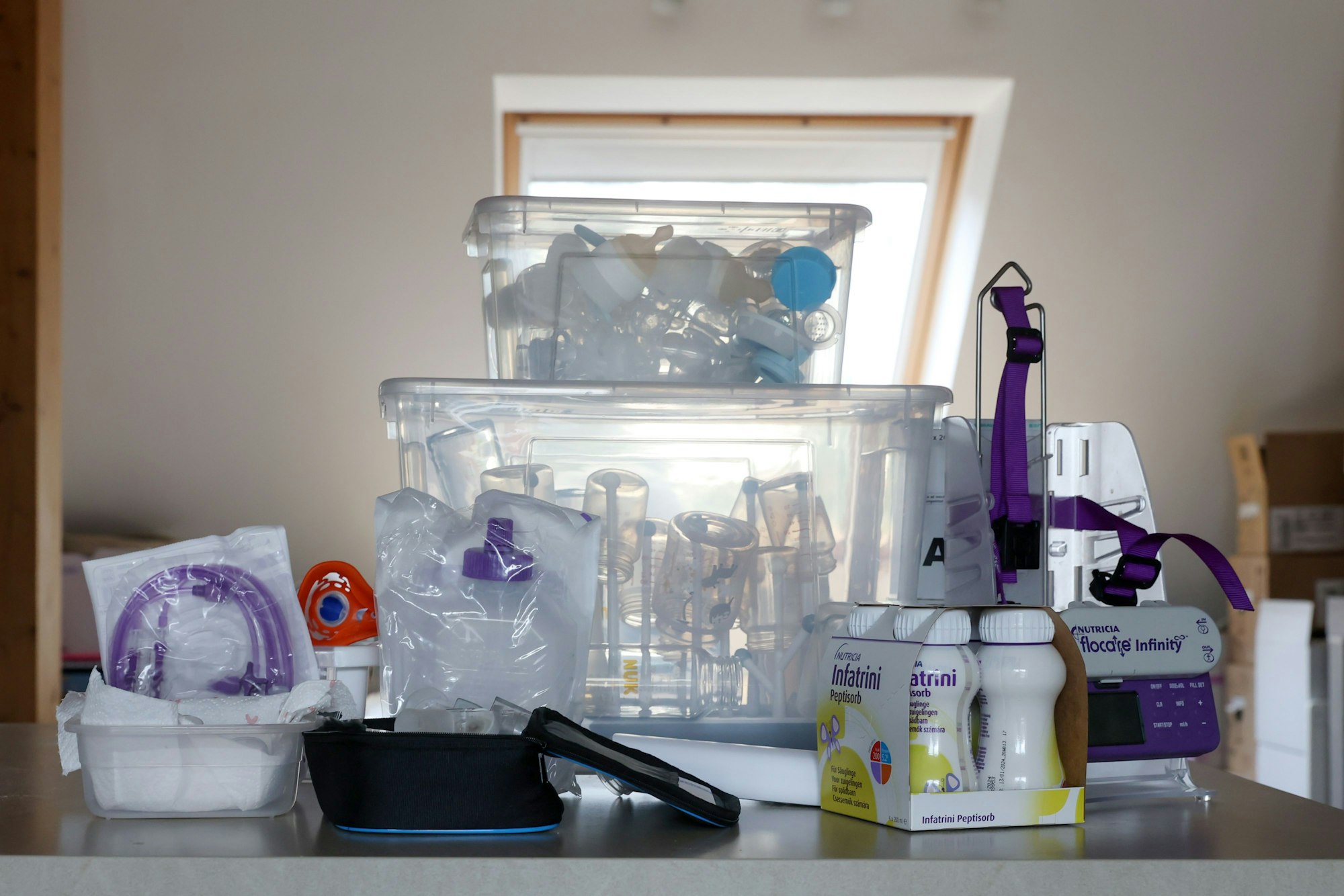 Schläuche, Spritzen und hochkalorische Säuglingsnahrung stehen auf dem Küchenbüffet.