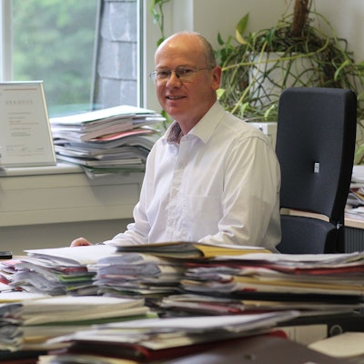 Ein Mann sitzt an einem Schreibtisch voller Akten