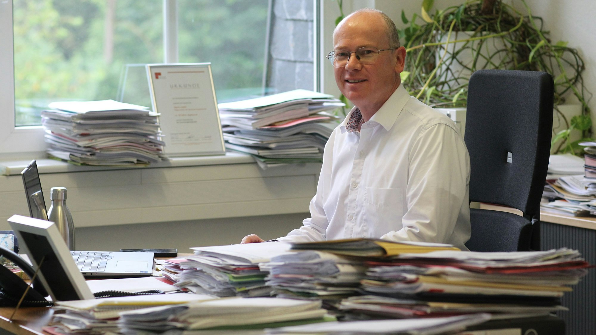 Ein Mann an einem Schreibtisch voller Akten