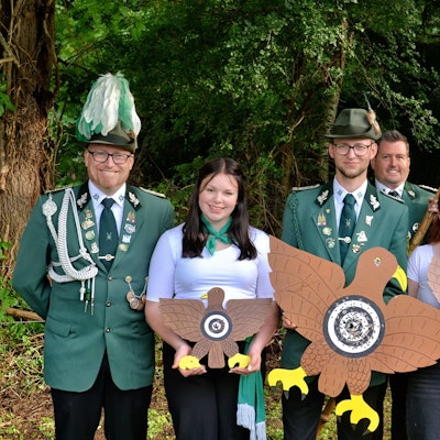 Die Nemmenicher Schützen psieren in Uniformen und halten Vögel und Fahne.