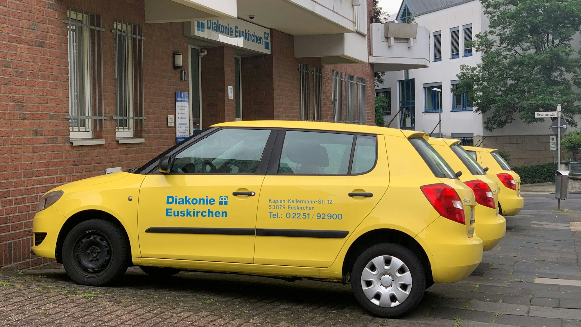 Vor dem Gebäude der Diakonie Euskirchen stehen mehrere Autos des Wohlfahrtsverbandes in der typisch gelben Farbe.