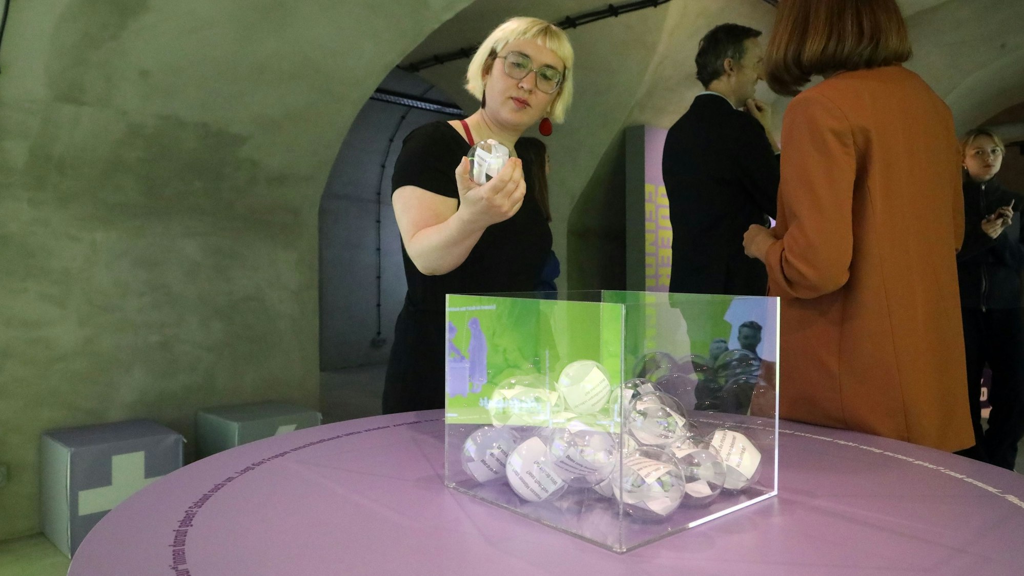 Eine Frau hält eine Kugel in der Hand, in der sich Papierschnipsel mit Text befinden.