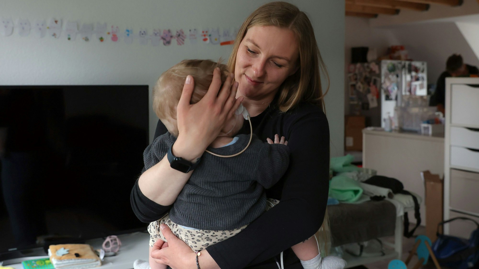 Sandra Leuschen trägt ihre Tochter Lucy in ihrer Wohnung in Ehrenfeld..