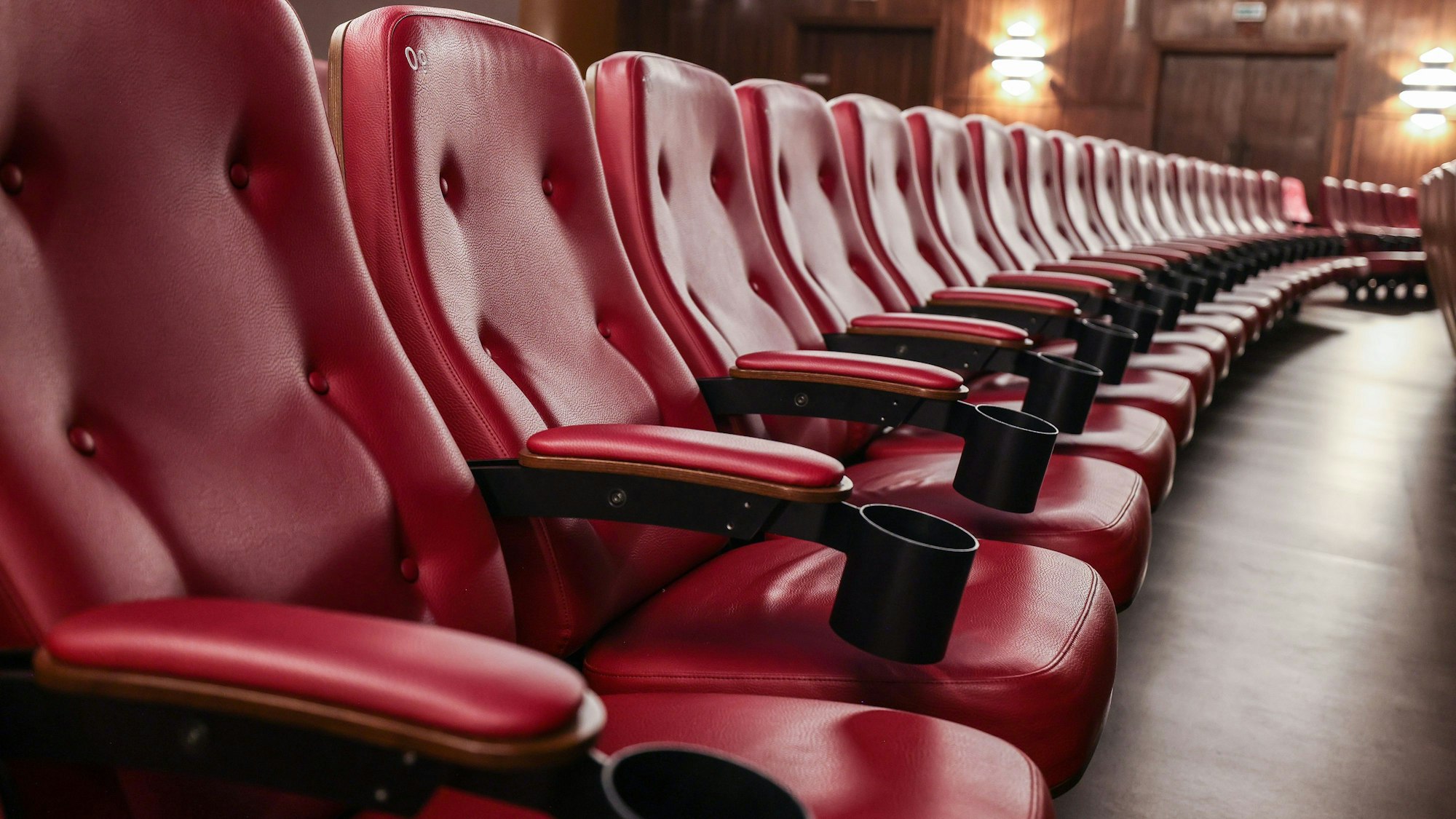 Rote Sessel stehen in einem Kinosaal.