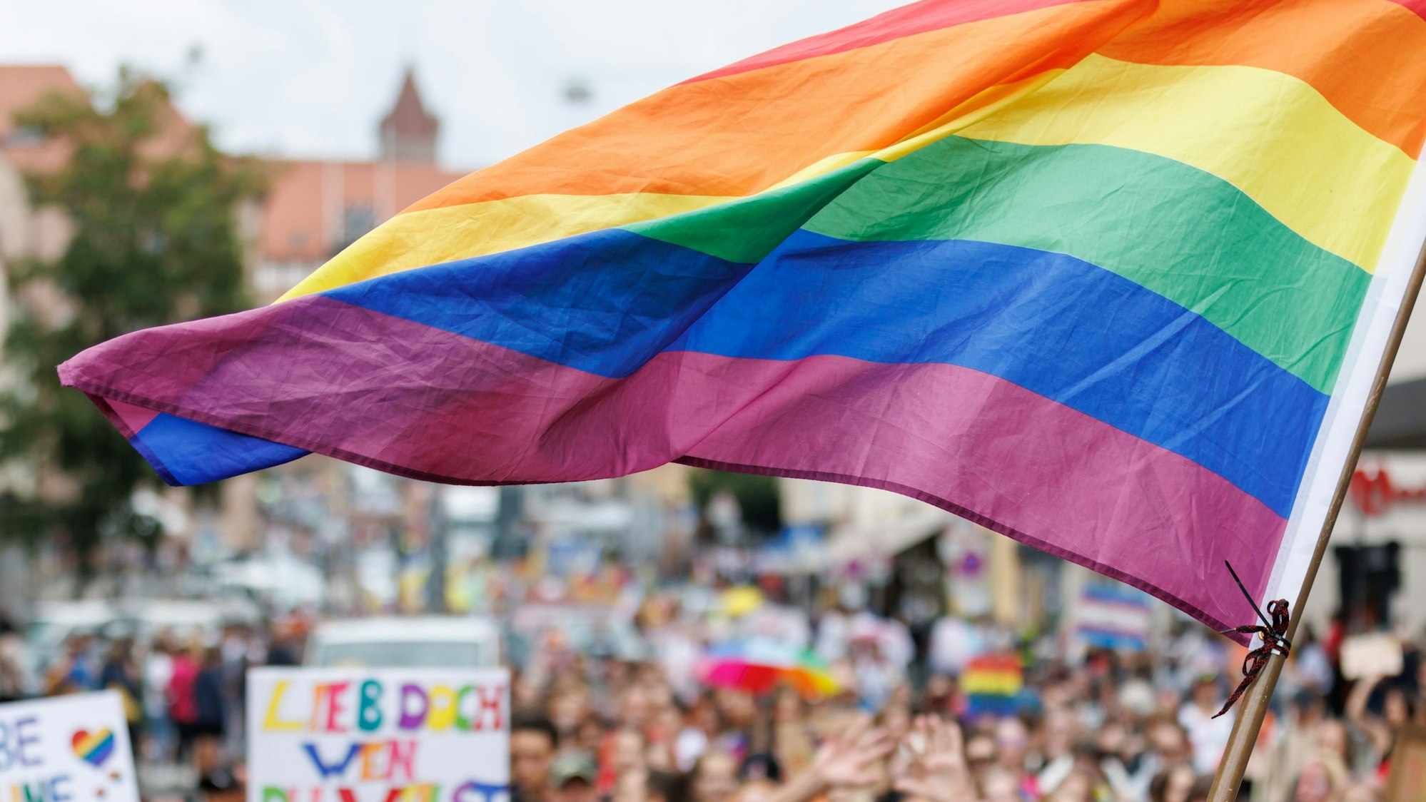 Große Regenbogenflagge weht über einer Menschenmenge