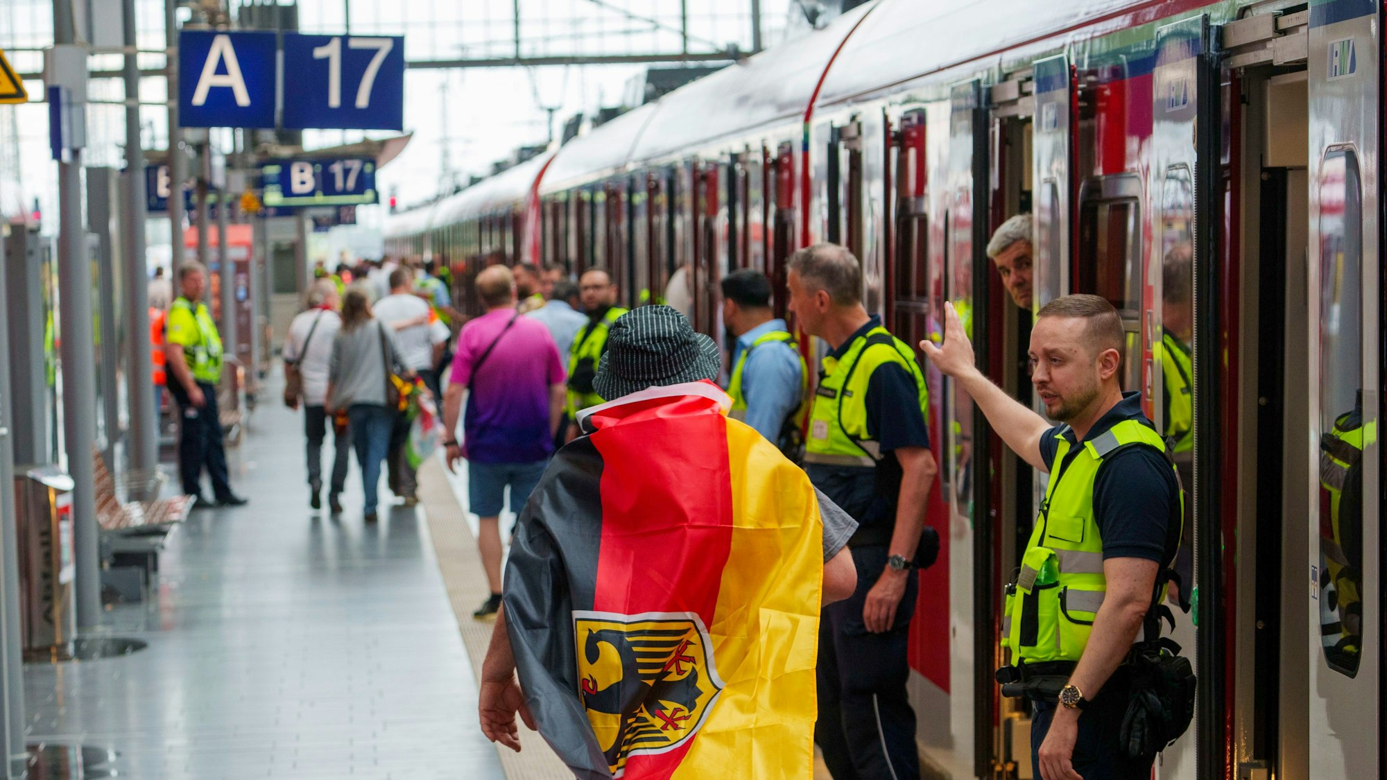 23.06.2024, Hessen, Frankfurt/Main: Fußball, UEFA Euro 2024, EM, Schweiz - Deutschland, Vorrunde, Gruppe A, Spieltag 3, Frankfurt Arena, Sicherheitspersonal der Bahn weisst einem deutschen Fan den Weg zu einem freien Abteil, ganz am Ende des Zuges. Fussballfans die mit dem Zug ab Hauptbahnhof zum Deutsche Bank Park, dem Austragungsort der Begegnung Schweiz - Deutschland, kommen wollen, werden hart geprüft. Die Menschen müssen in völlig überfüllten und verspäteten Zügen bei hohen Temperaturen ausharren. Foto: Andreas Arnold/dpa +++ dpa-Bildfunk +++