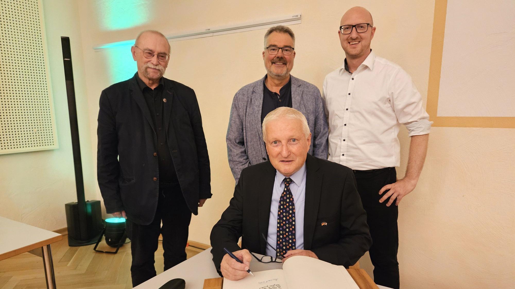 Dr. Michael Röös trägt sich ins Goldene Buch der Stadt Schleiden ein, dahinter stehen Philipp Cuck, Erik Schumacher und Ingo Pfennings.