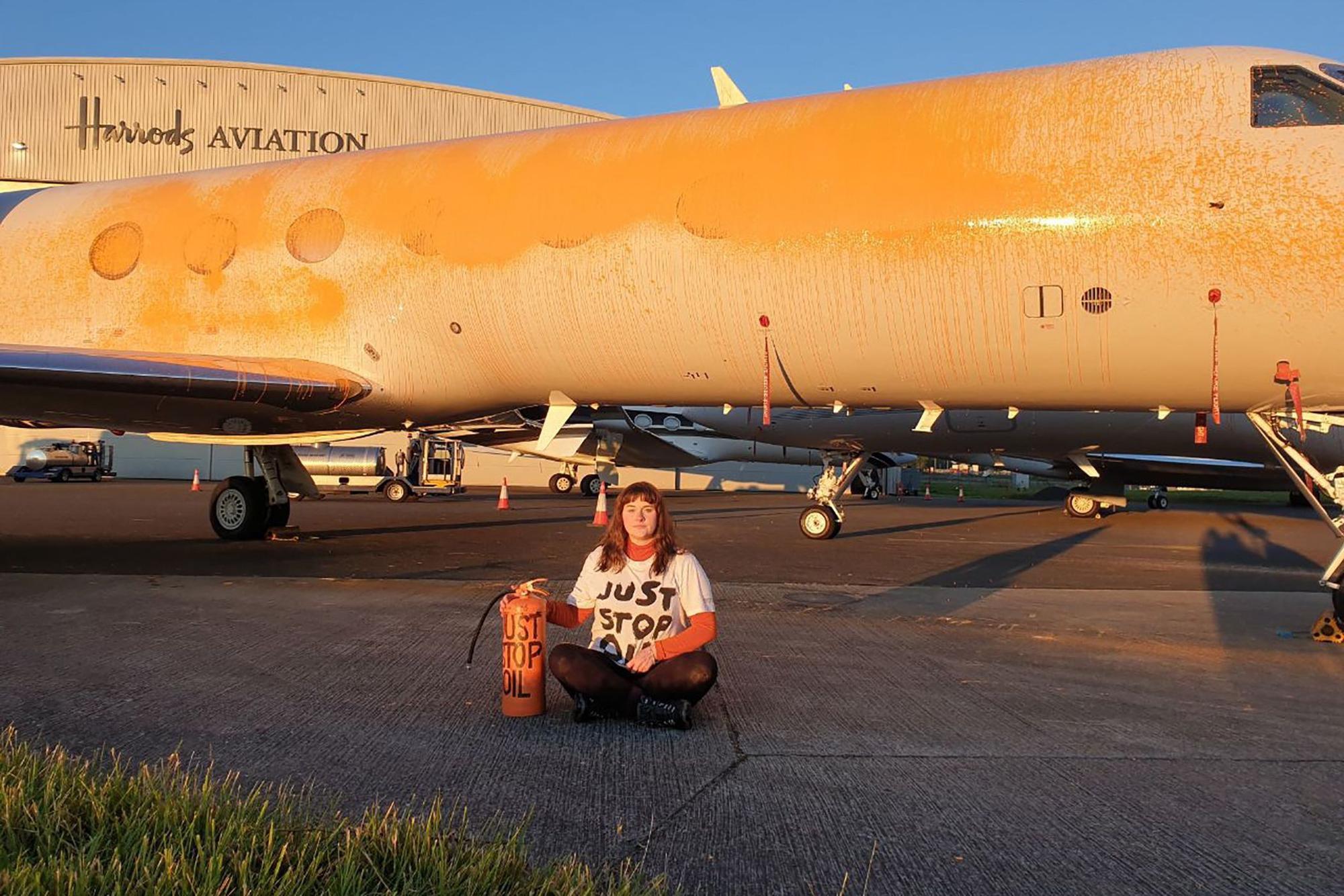 Das von „Just Stop Oil“ veröffentlichte Bild zeigt eine Klimademonstrantin, die geparkte Privatjets am Londoner Flughafen Stansted in Essex mit orangefarbener Farbe besprühen.