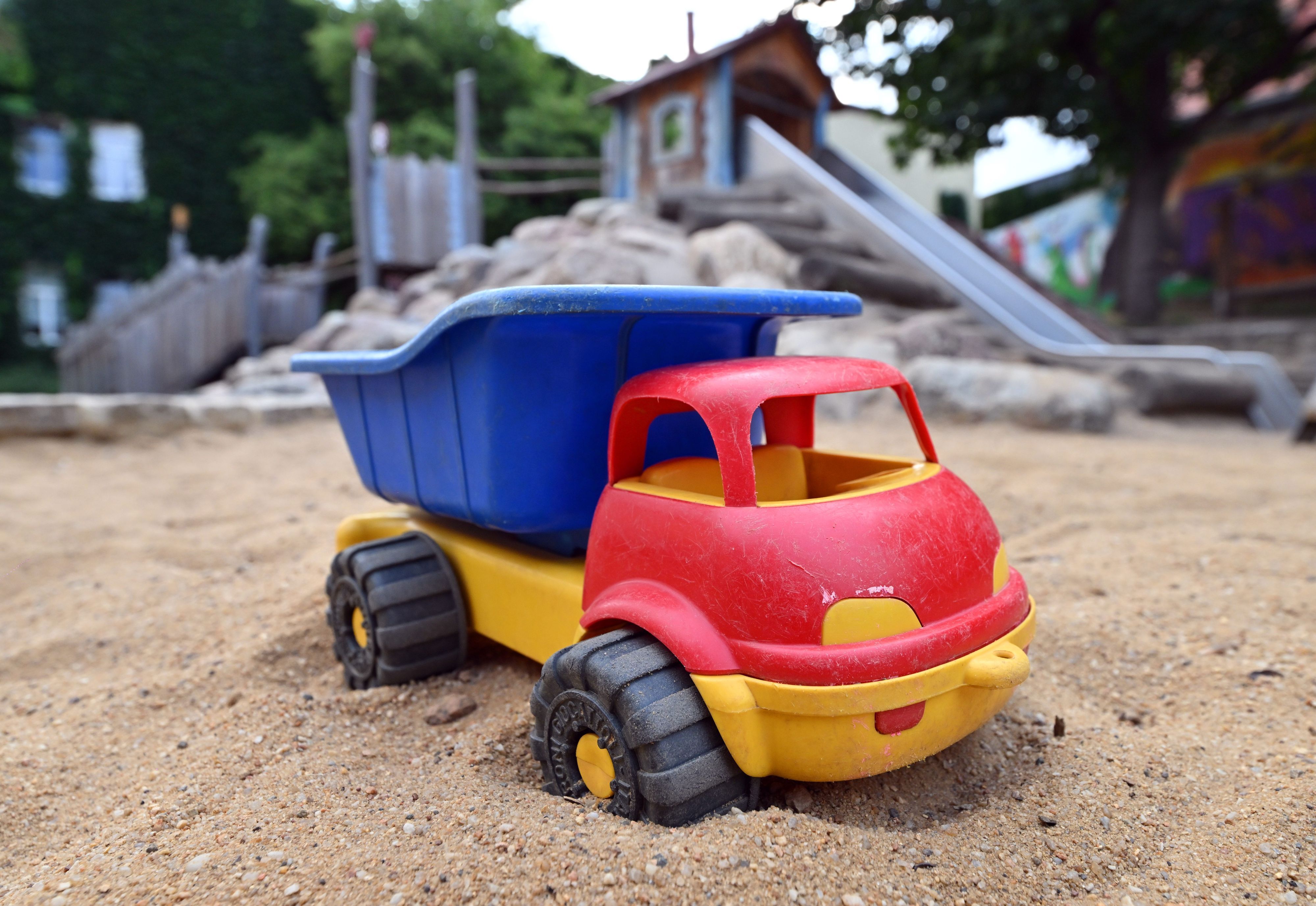 Ein Spielzeuglaster in einem Sandkasten auf einem Spielplatz.