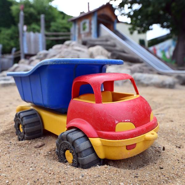 Ein Spielzeuglaster in einem Sandkasten auf einem Spielplatz.