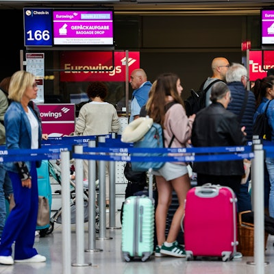 03.07.2024, Nordrhein-Westfalen, Düsseldorf: Passagiere stehen am Flughafen in einer Warteschlange vor den Gepäckaufgabe- und Check-In-Schaltern von Eurowings. Foto: Christoph Reichwein/dpa +++ dpa-Bildfunk +++
