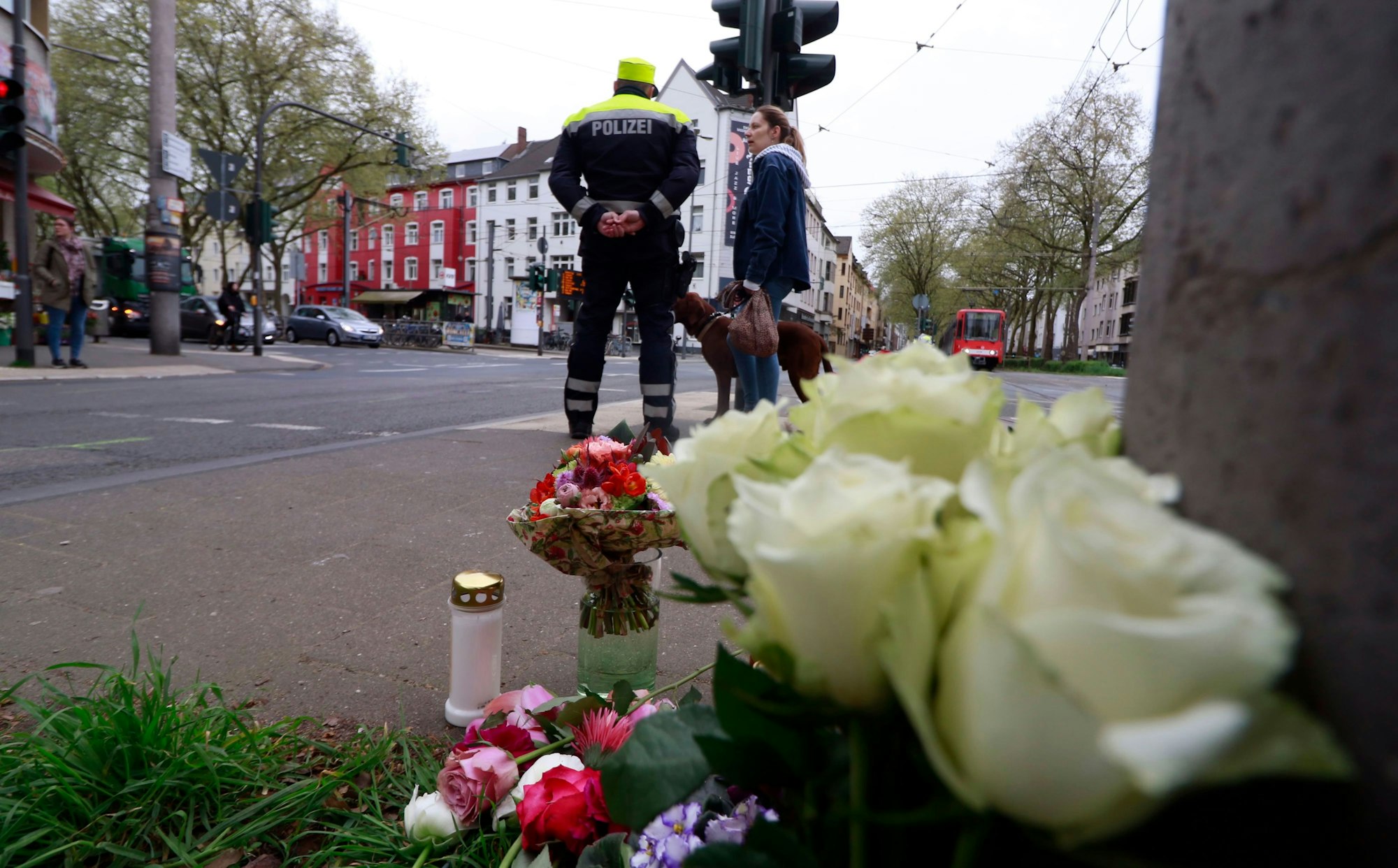 Blumen und Polizei am Unfallort an der Ecke Sülzgürtel/Luxemburger Straße für die 63-jährige Radfahrerin, die im April 2023 hier verstarb.