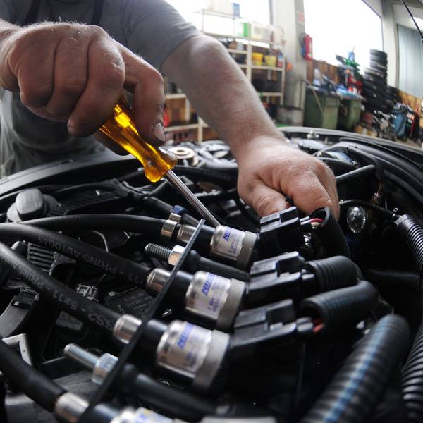 Ein Mechaniker arbeitet in einer Autowerkstatt im Motorraum eines Fahrzeugs mit Gasantrieb.