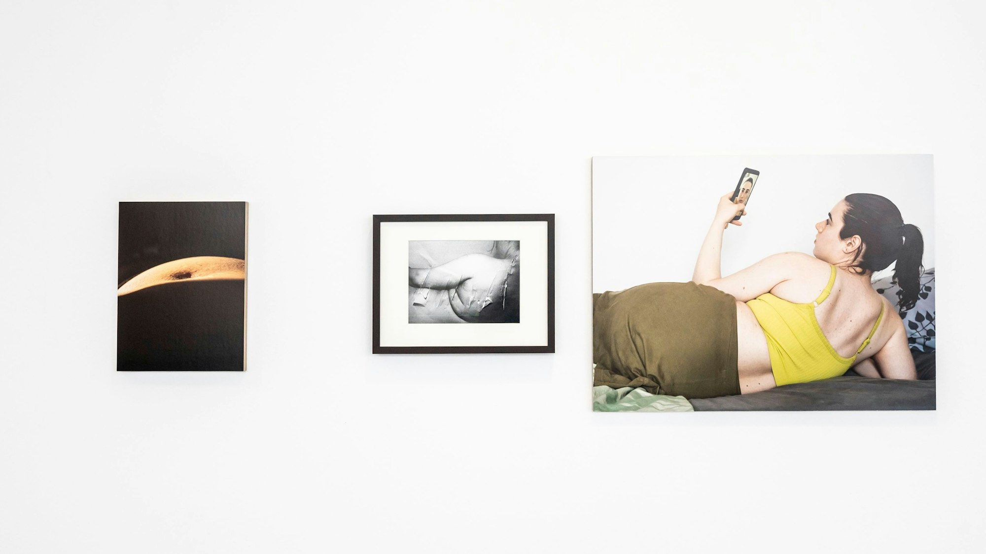 Drei Bilder hängen an einer Wand.