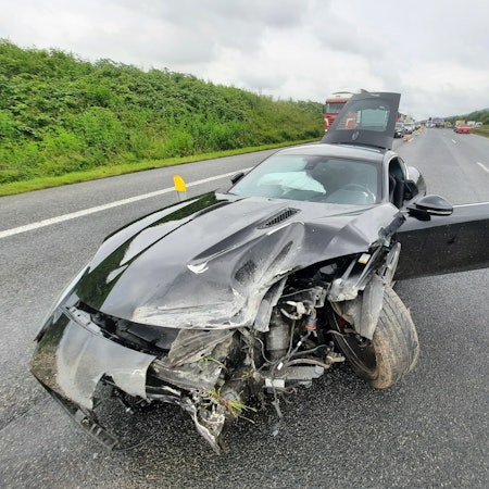 Ein Sportwagen steht auf der Autobahn, die Front des Fahrzeugs ist erheblich beschädigt.