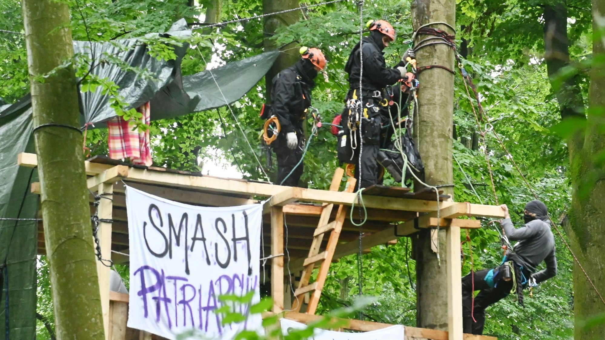 Ein Baumschützer seilt sich während der Räumung vor den Augen von Polizisten vom Baumhaus ab.