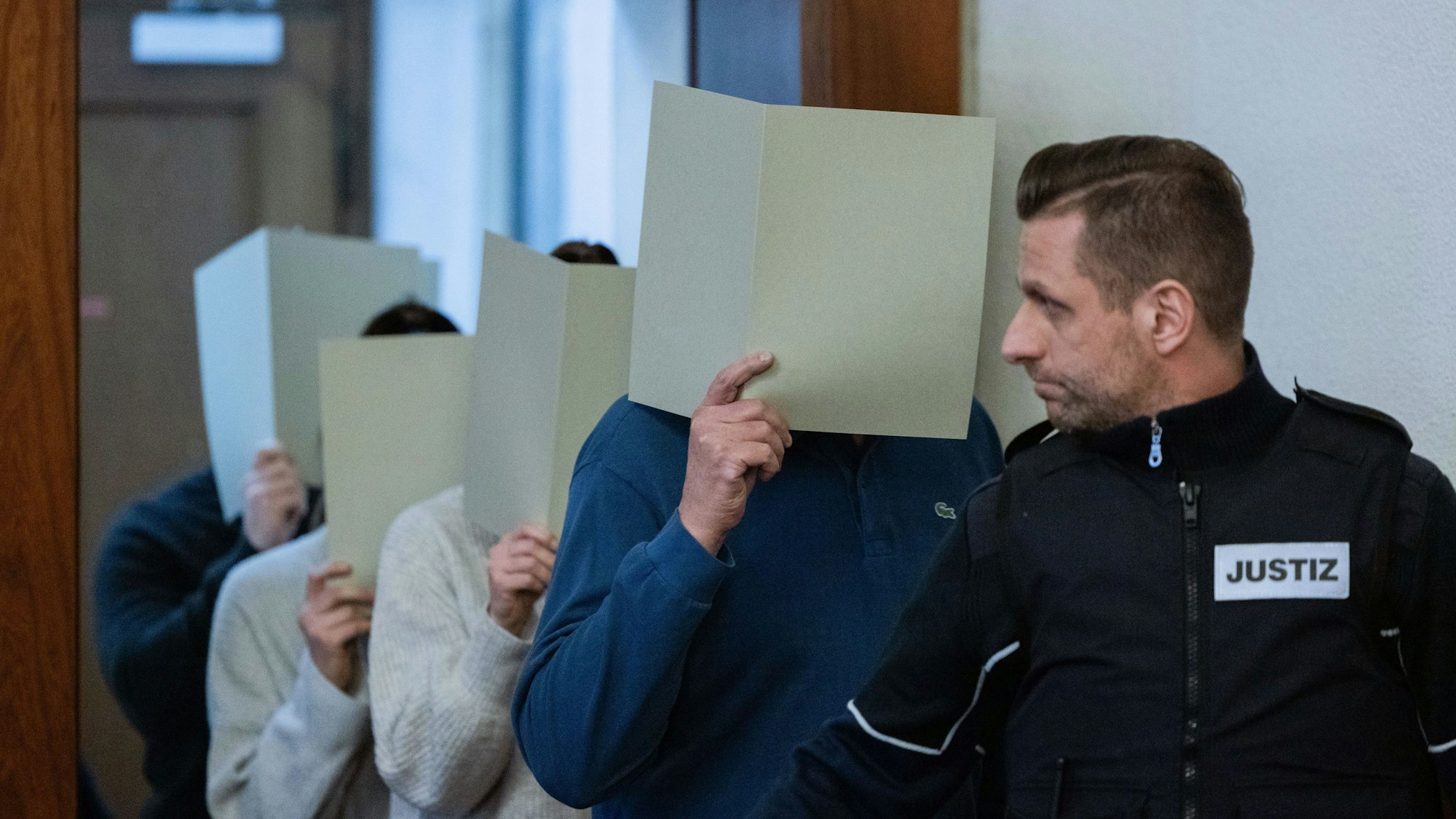 Die fünf angeklagten Polizeibeamtinnen und -beamten kommen in den Gerichtssaal des Landgerichts.