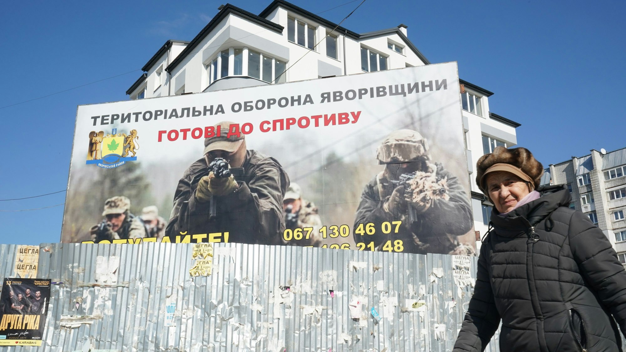 Eine Frau geht an einem Plakat vorbei, auf dem Soldaten im Einsatz zu sehen sind.