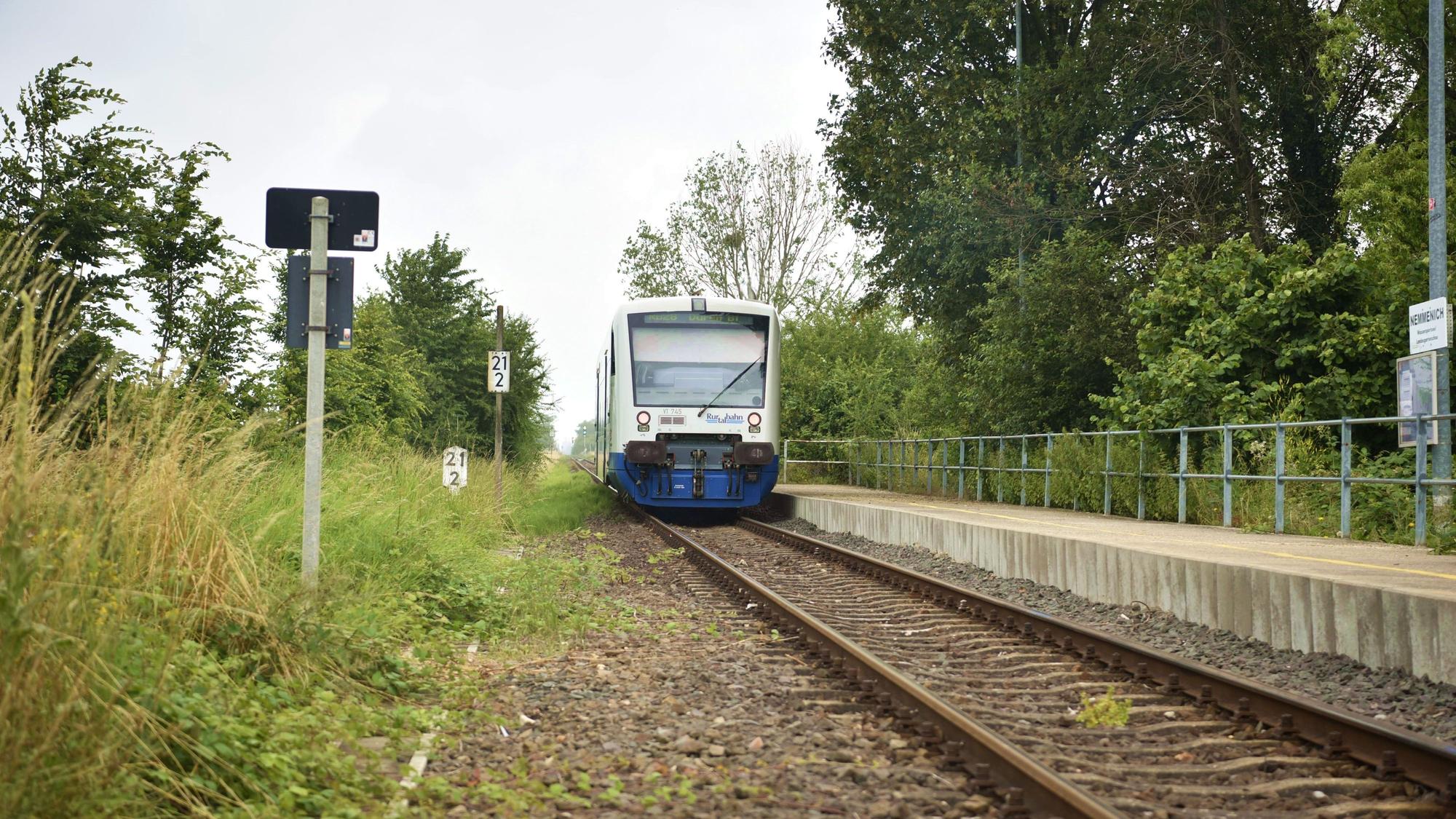 Ein Zug der Rurtalbahn fährt in Nemmenich am Bahnsteig ab.