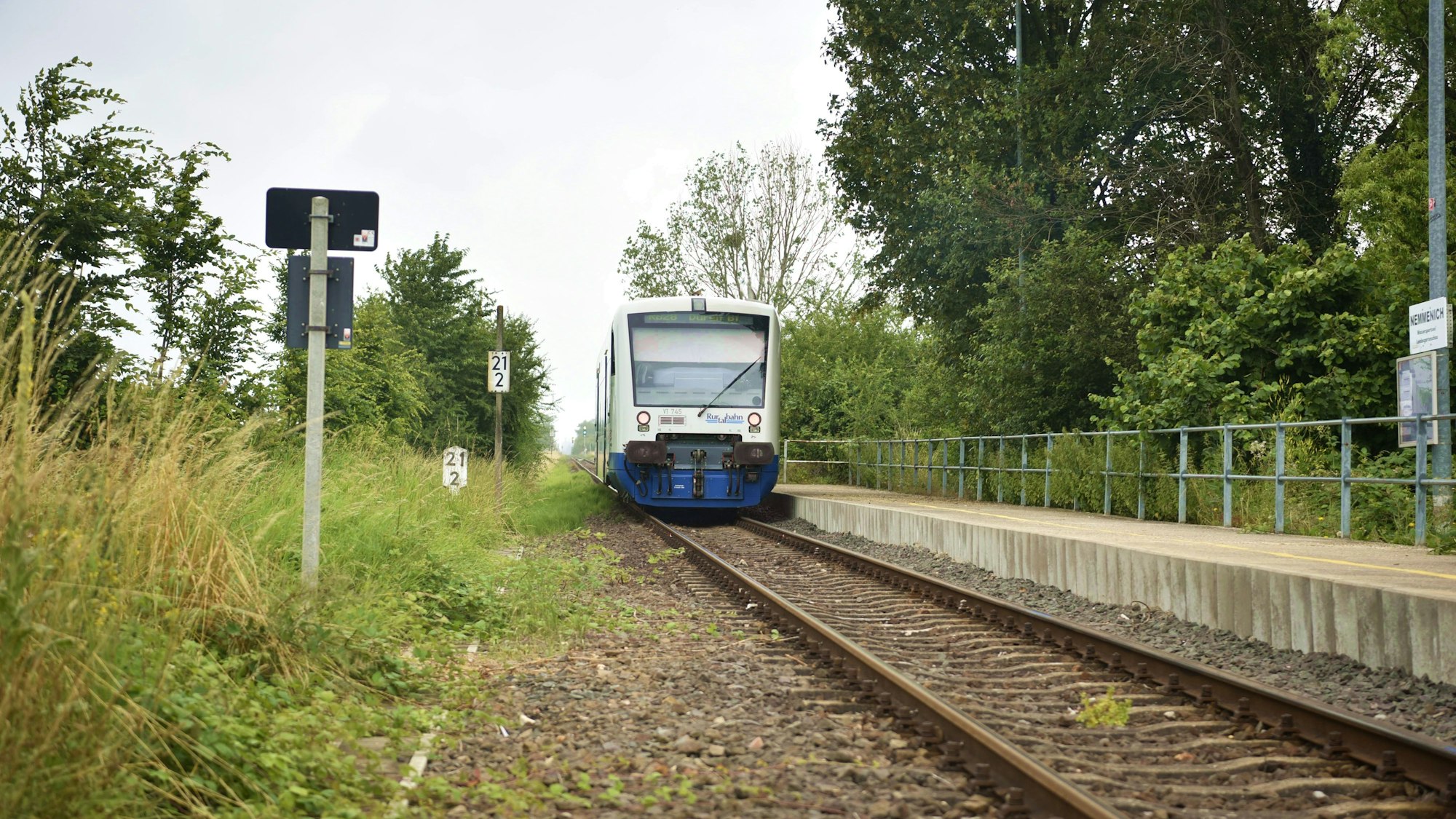 Ein Zug der Rurtalbahn fährt in Nemmenich am Bahnsteig ab.