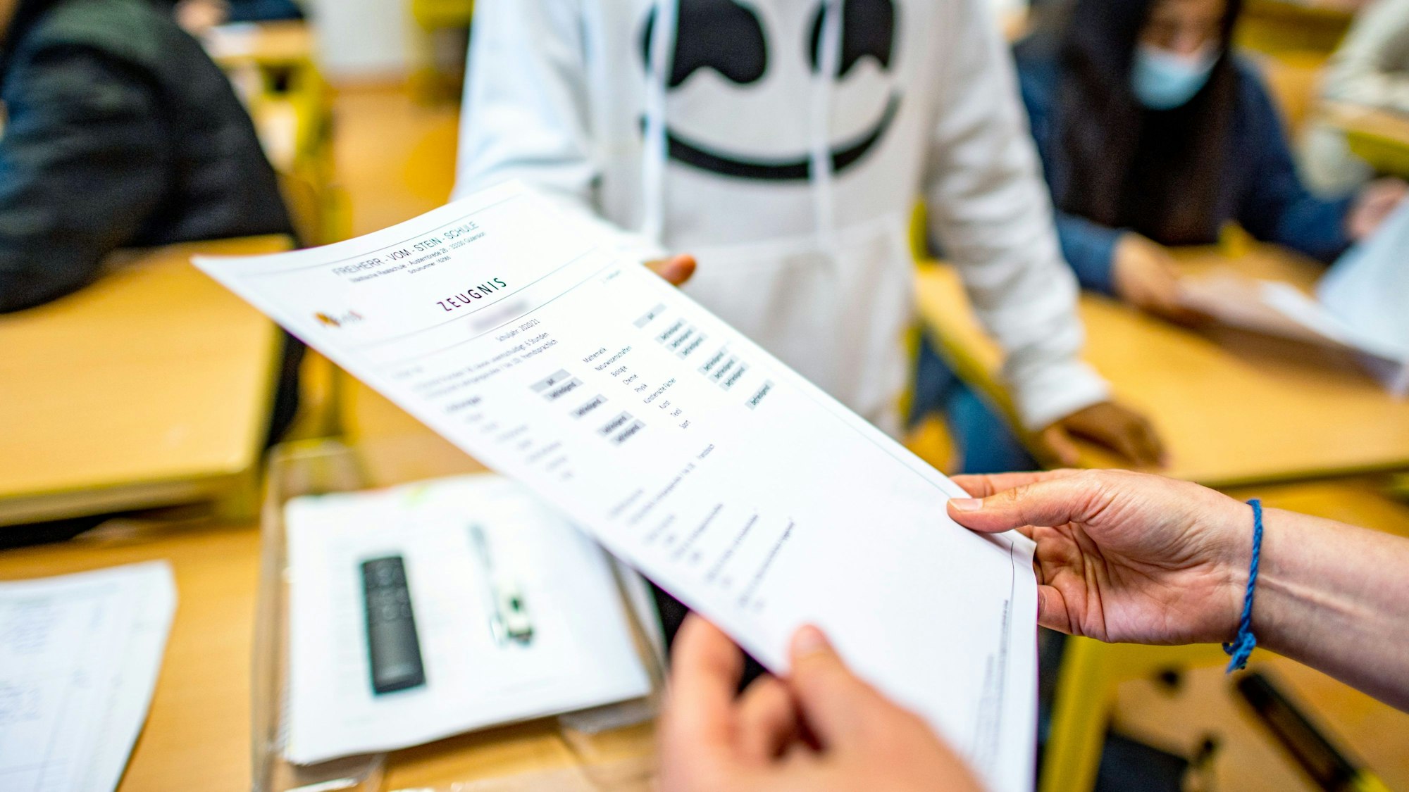 Die Klassenlehrerin übergibt das Zeugnis eines Schülers der Klasse 9b der Freiherr-vom-Stein-Schule in Gütersloh.