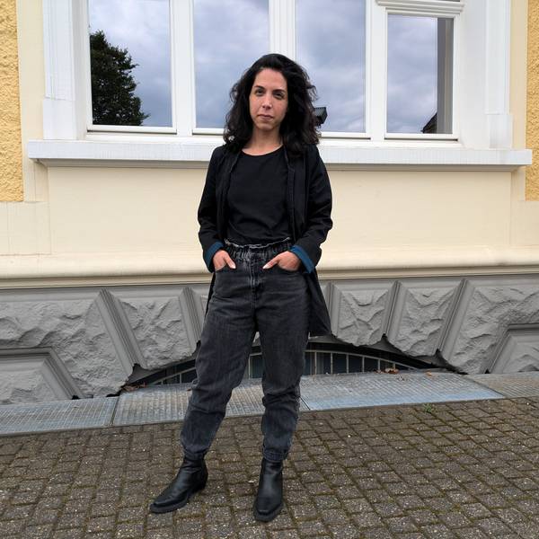 Eine Frau steht vor einer Hausfassade.