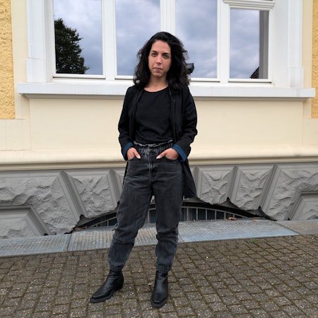 Eine Frau steht vor einer Hausfassade.