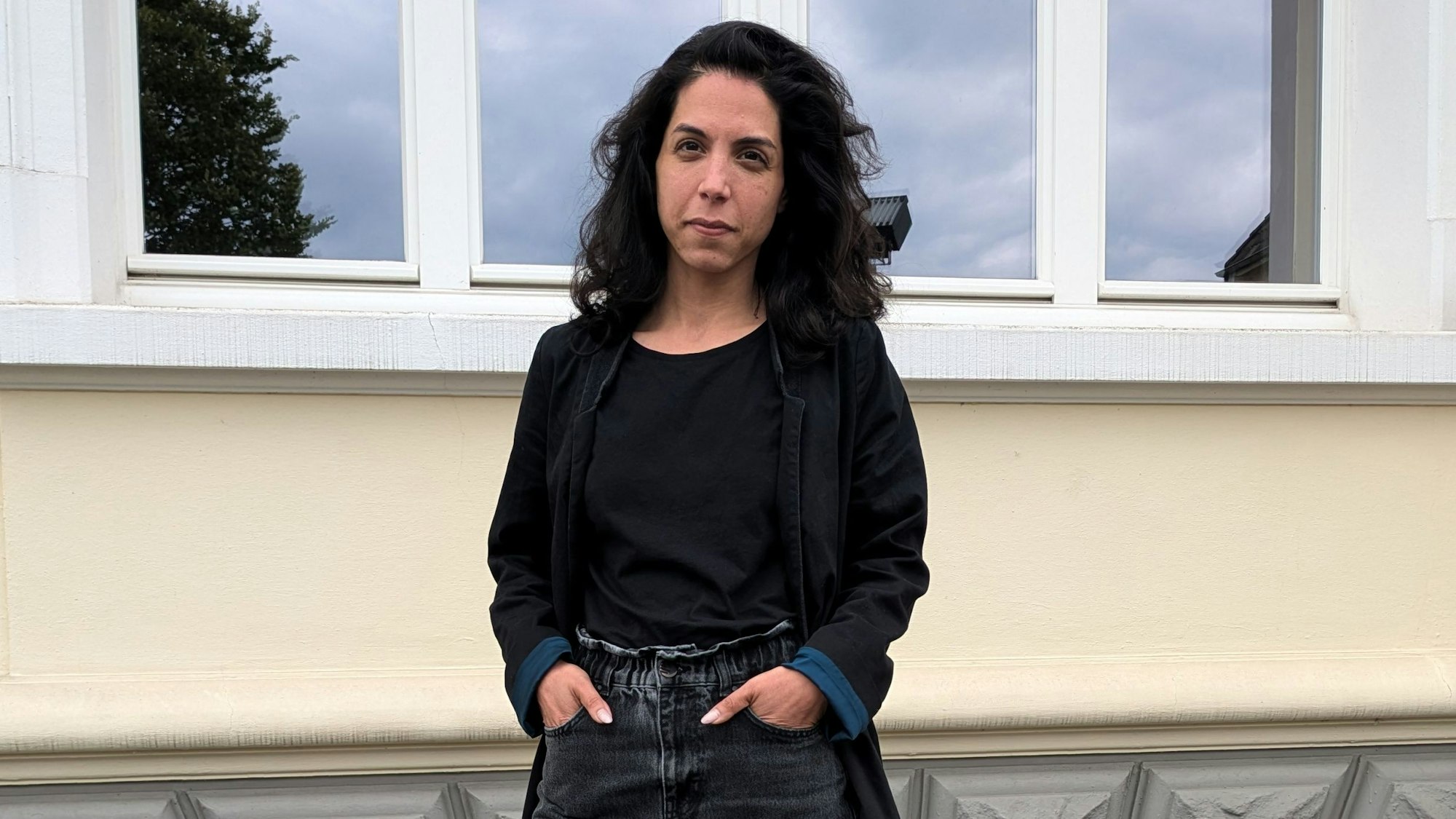 Eine Frau steht vor einer Hausfassade.