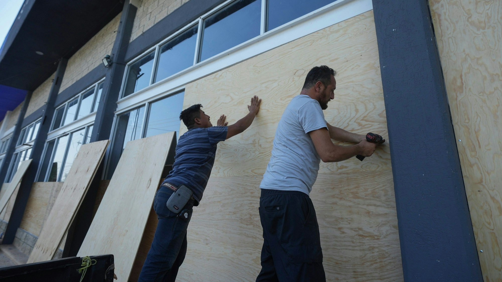 03.07.2024, Mexiko, Playa del Carmen: Mitarbeiter eines Möbelhauses verschalen die Fenster zum Schutz vor dem erwarteten Hurrikan "Beryl" .