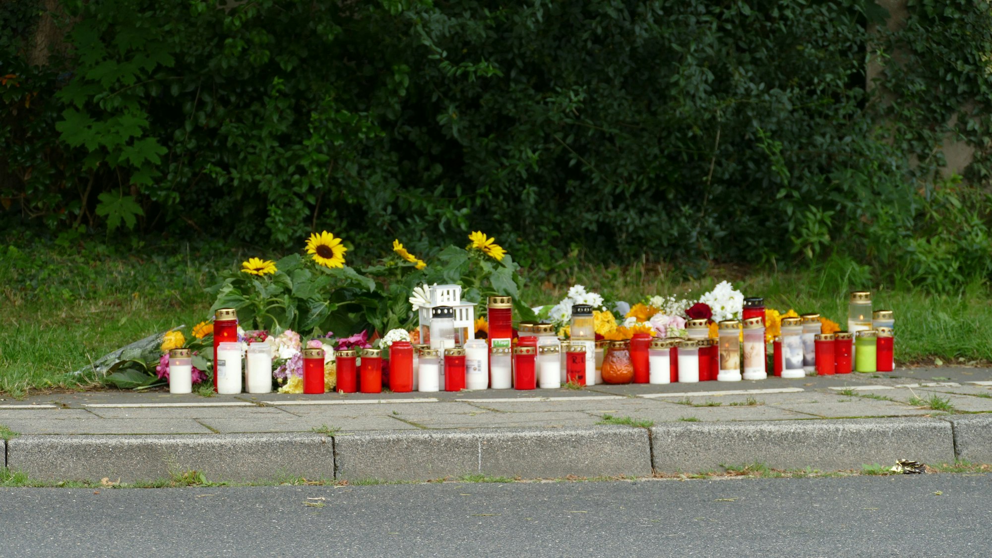 Menschen stehen an einer Gedenkstätte.