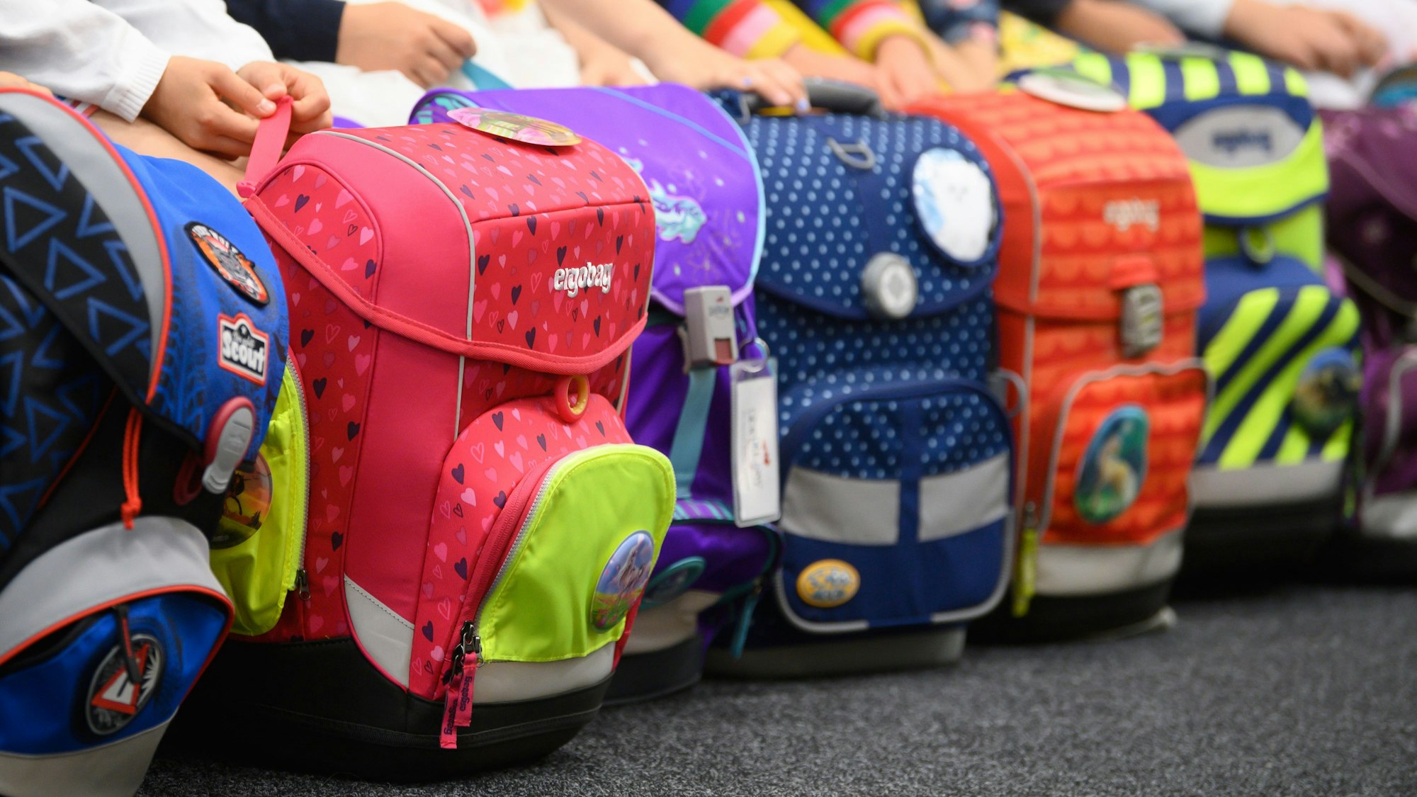 Eine Gruppe von Kindern präsentiert ihre bunten Schulranzen.