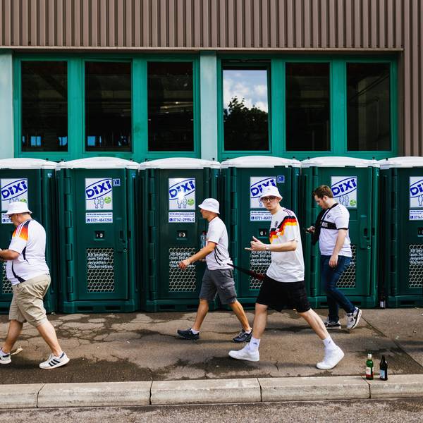 Deutsche Fans gehen beim Fanmarsch in der Innenstadt an mobilen Toiletten vorbei.