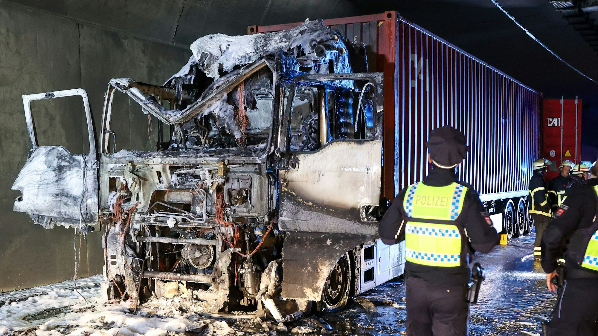 Einsatzkräfte stehen im Elbtunnel an einer ausgebrannten Lkw-Zugmaschine.