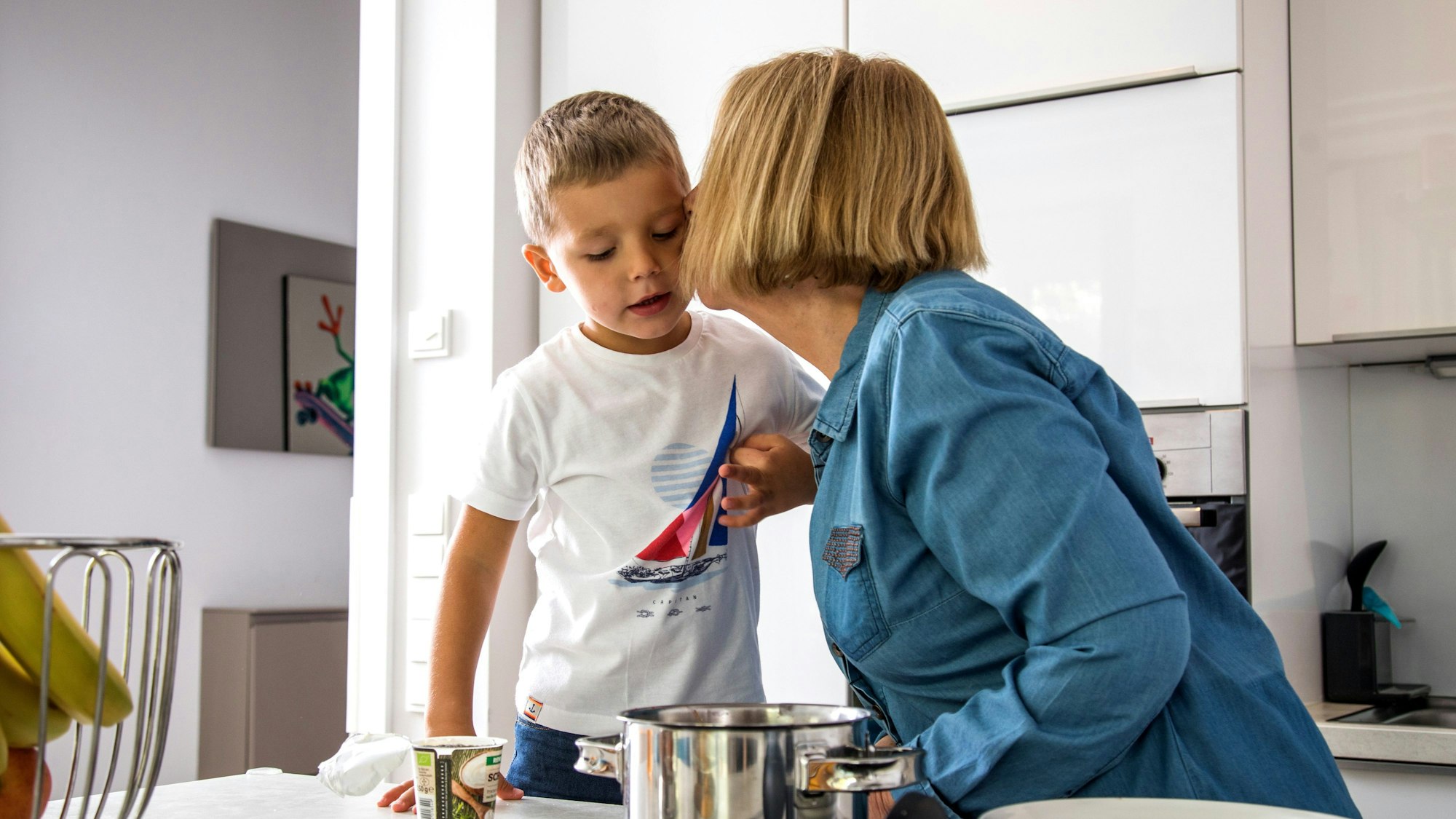 Ein Kind wird von einer weiblich gelesenen Person auf die Wange geküsst.