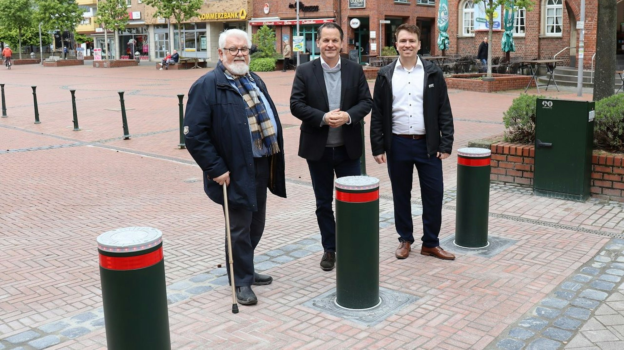 Drei Männer stehen vor hochgefahrenen Pollern.