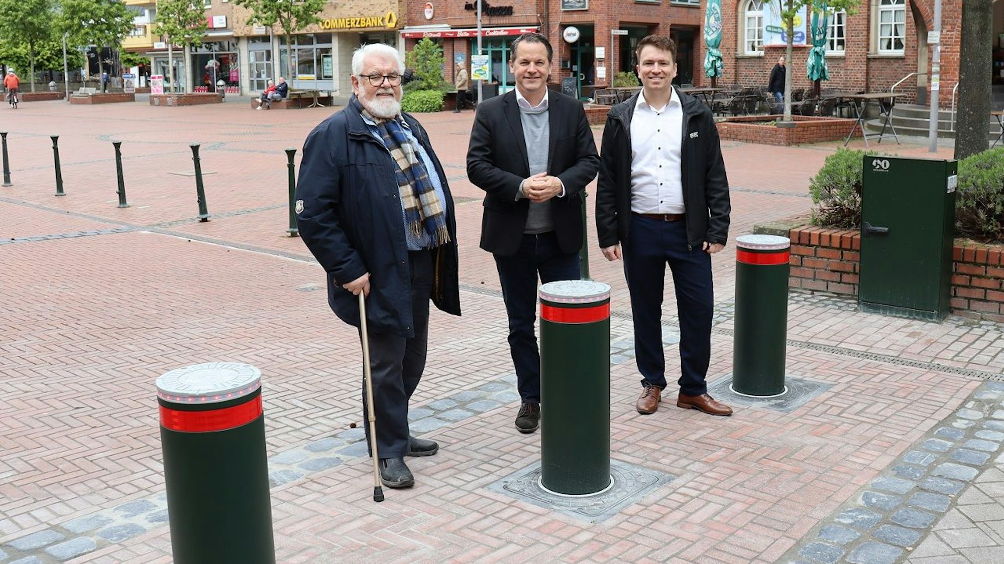 Drei Männer stehen hinter hochgefahrenen hydraulischen Pollern.