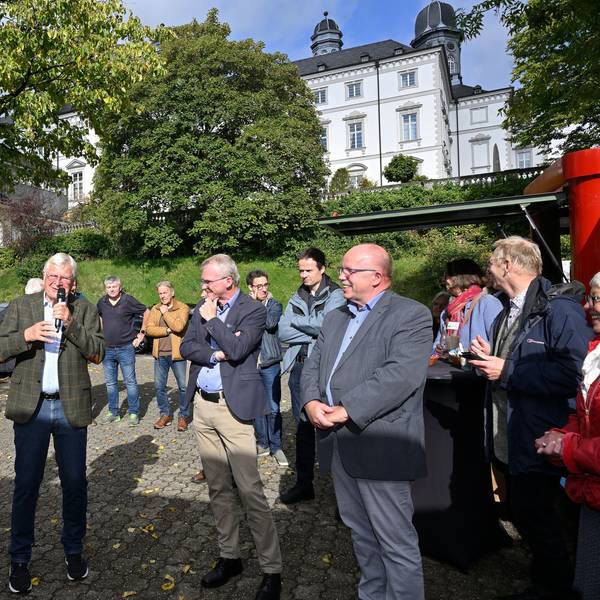 Viele Menschen stehen auf einem kleinen Platz, dahinter sieht man die Türme von Schloss Bensberg.