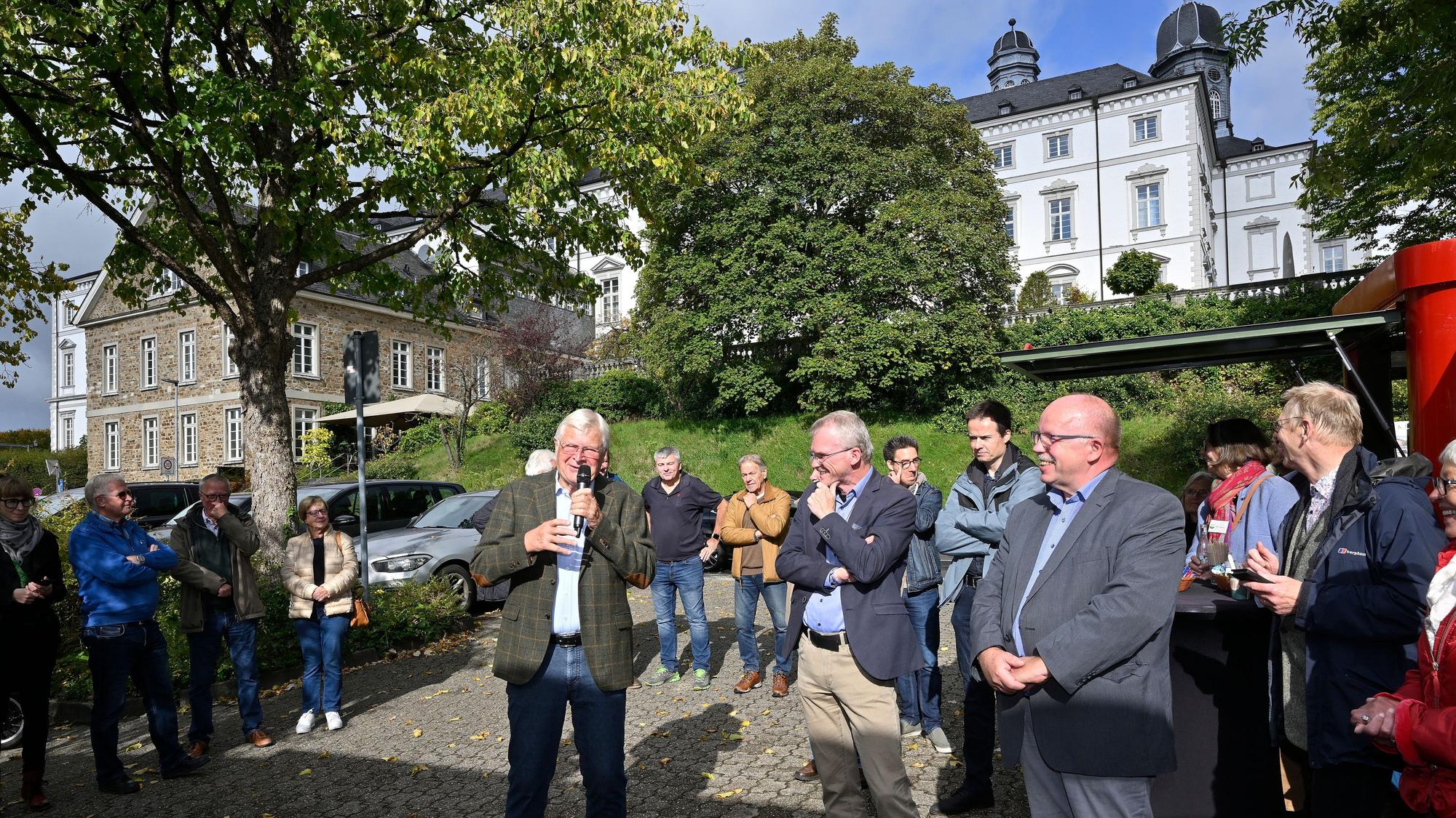 Viele Menschen stehen unterhalb der Türme eines Barockschlosses.