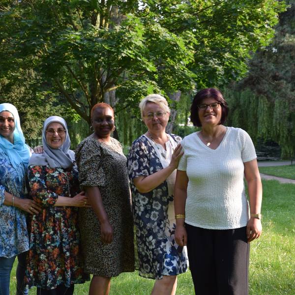 Mehrere Frauen unterschiedlicher Herkunft stehen in einem Park nebeneinander.