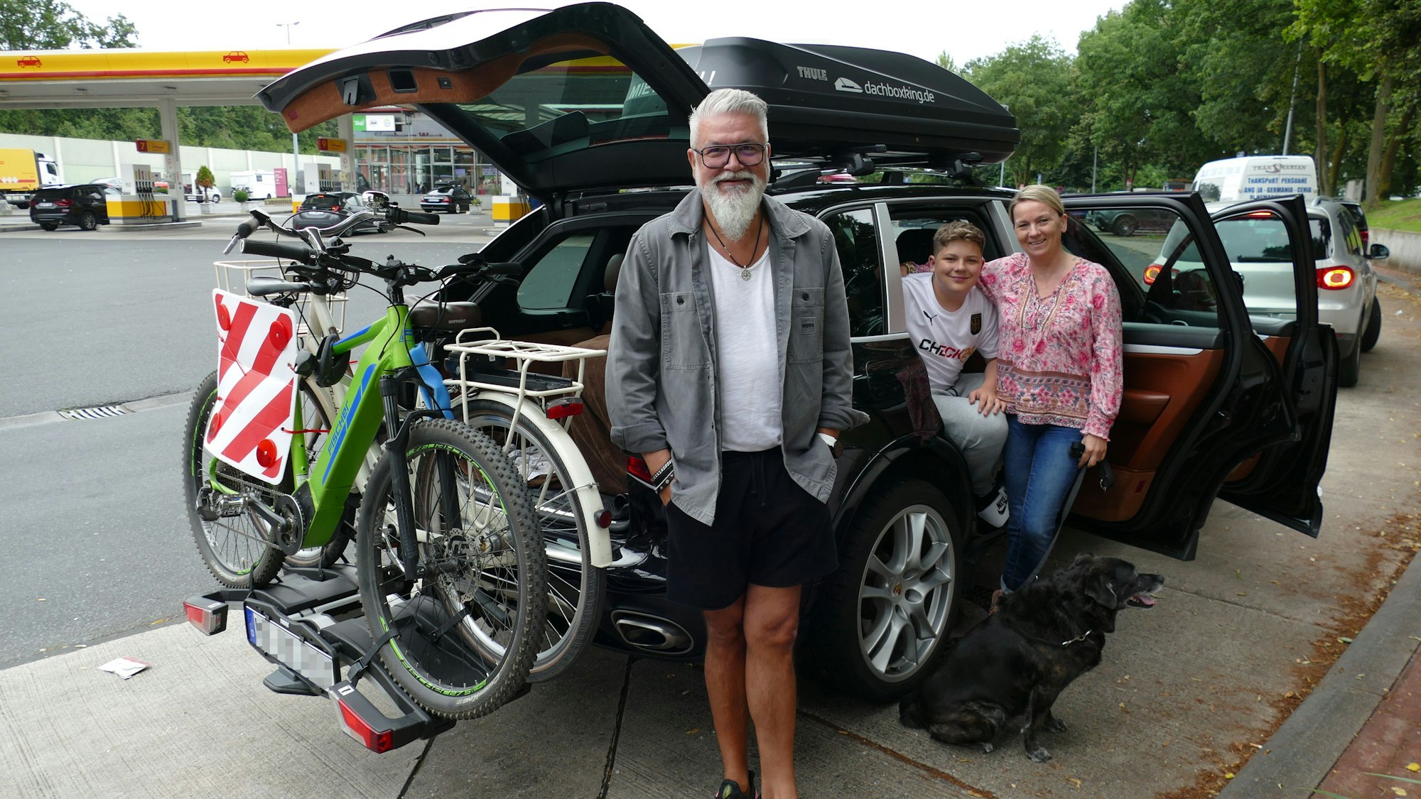 Eine Familie steht vor dem Auto.
