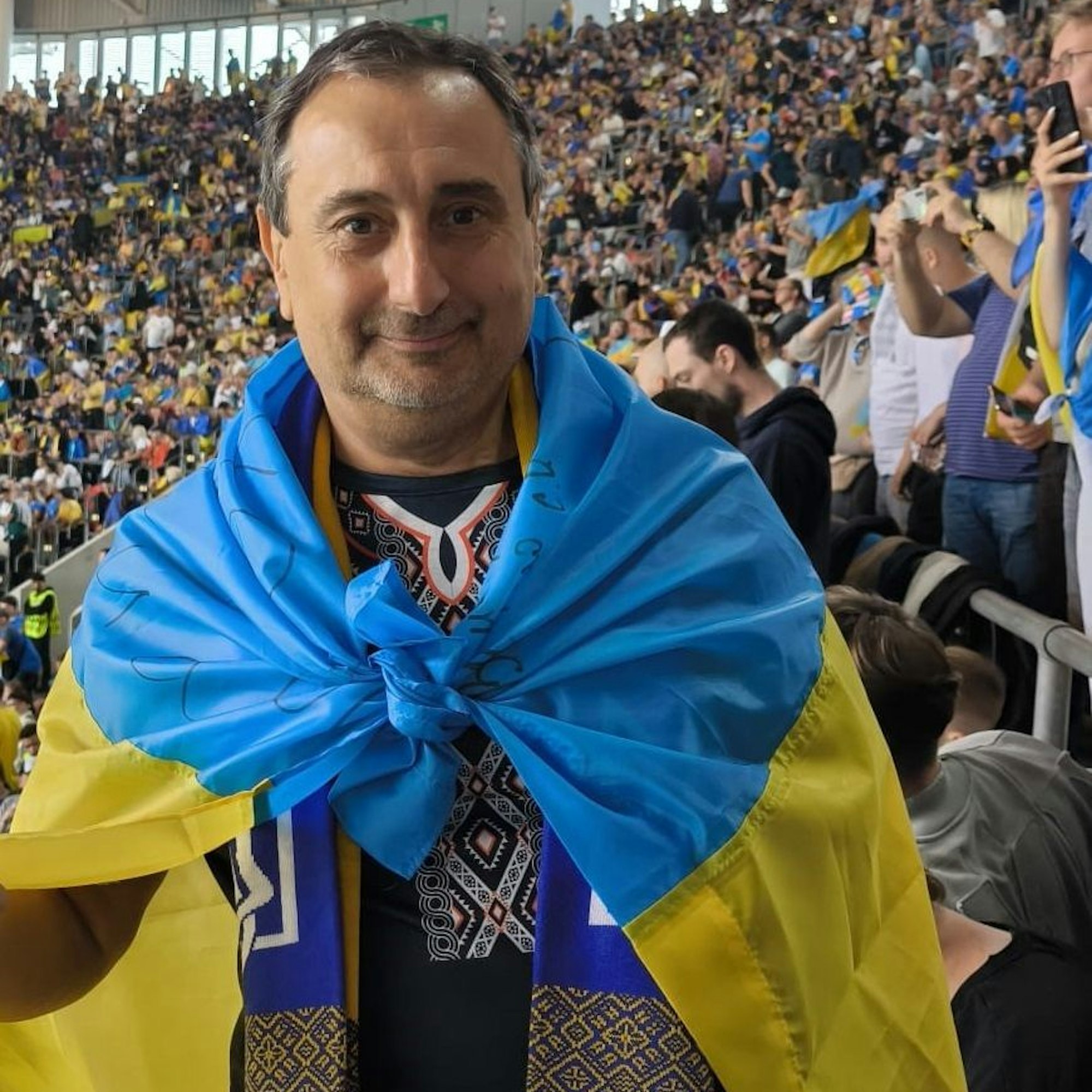Igor Prudkov im Stadion in Düsseldorf beim Spiel der Ukraine gegen Slowenien. Prudkov hat sich eine Ukraine-Fahne umgehängt.