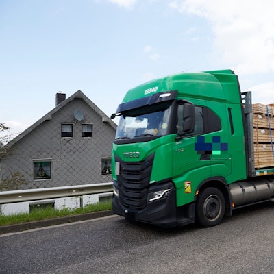 Ein Lkw fährt an einem Haus vorbei.