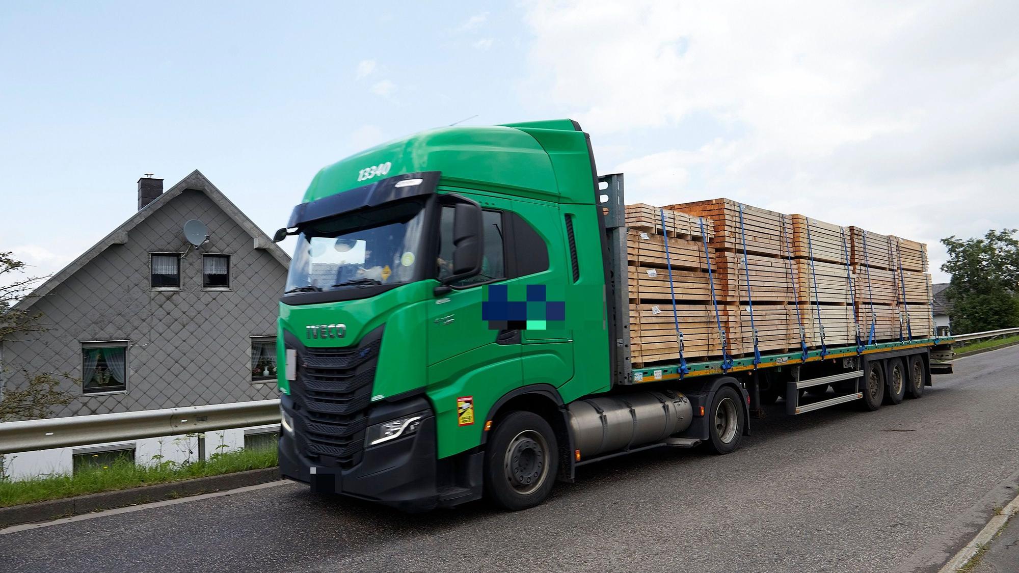 Ein Lkw fährt an einem Haus vorbei.