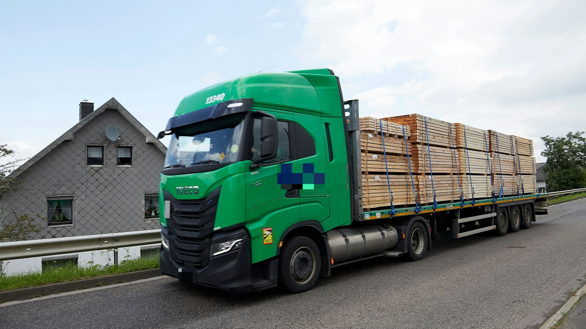 Ein Lkw fährt an einem Haus vorbei.