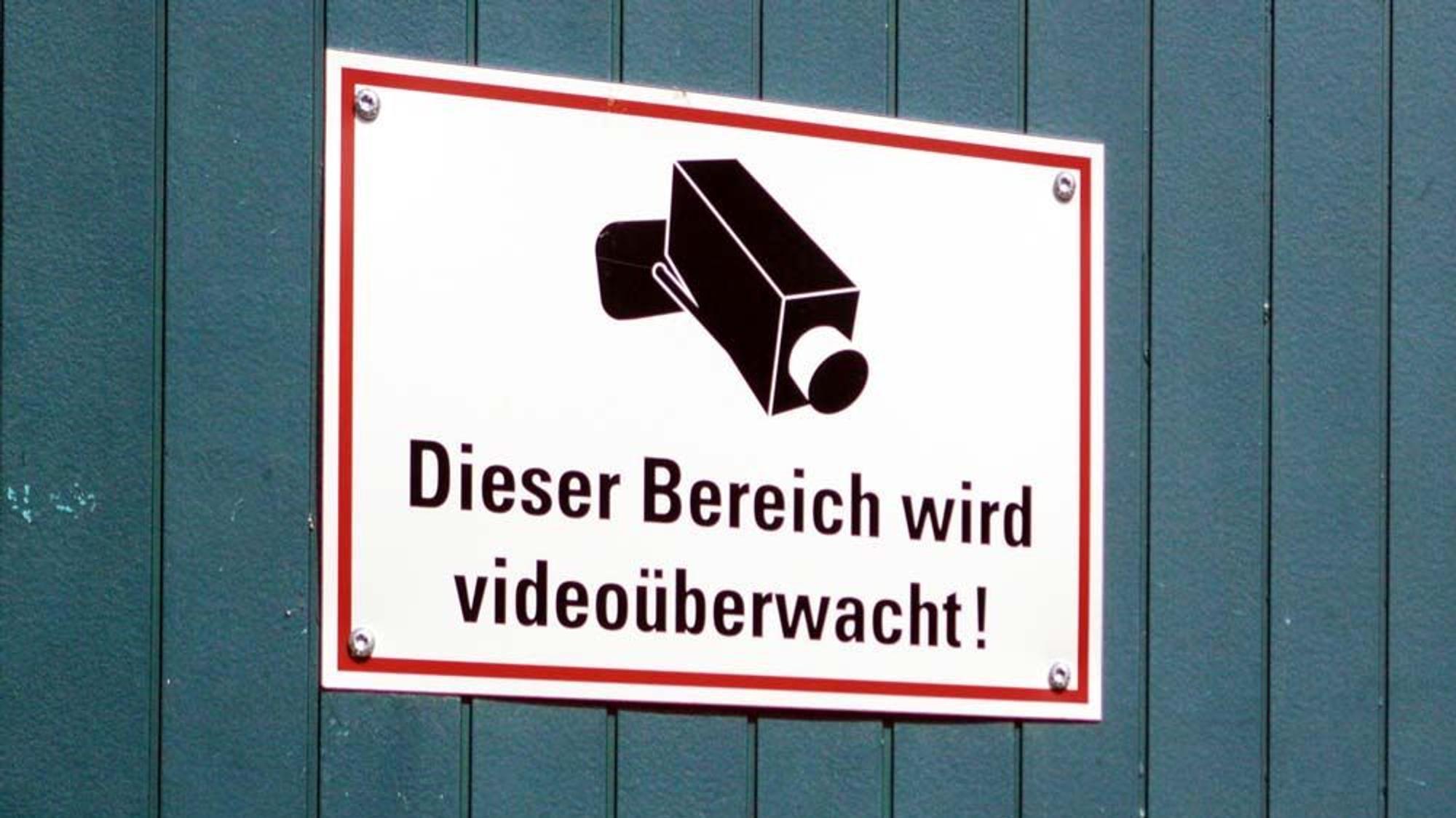 Auf einem Schild wird darauf hingewiesen, dass ein Bereich mit Kameras überwacht wird.