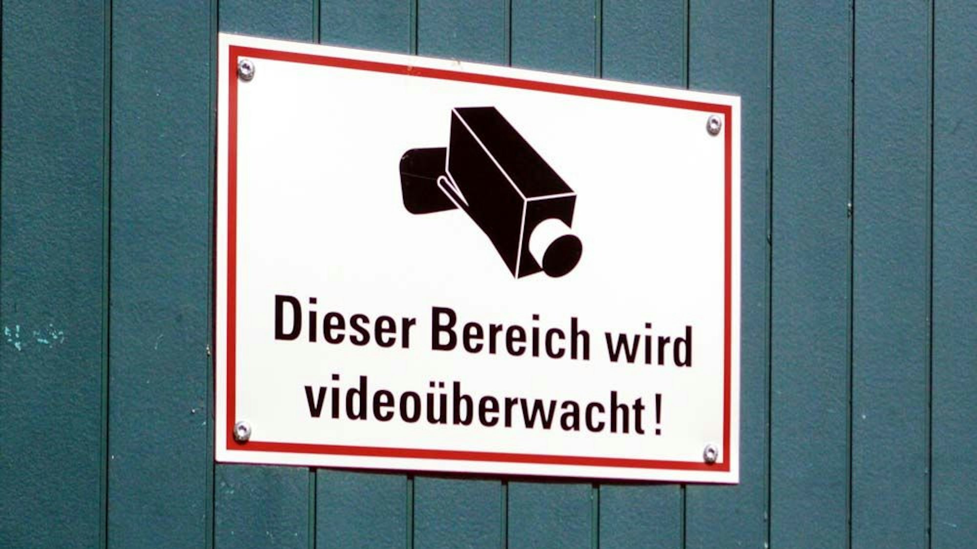 Auf einem Schild wird darauf hingewiesen, dass ein Bereich mit Kameras überwacht wird.